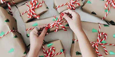 Woman's hands tying a striped bow on a small gift